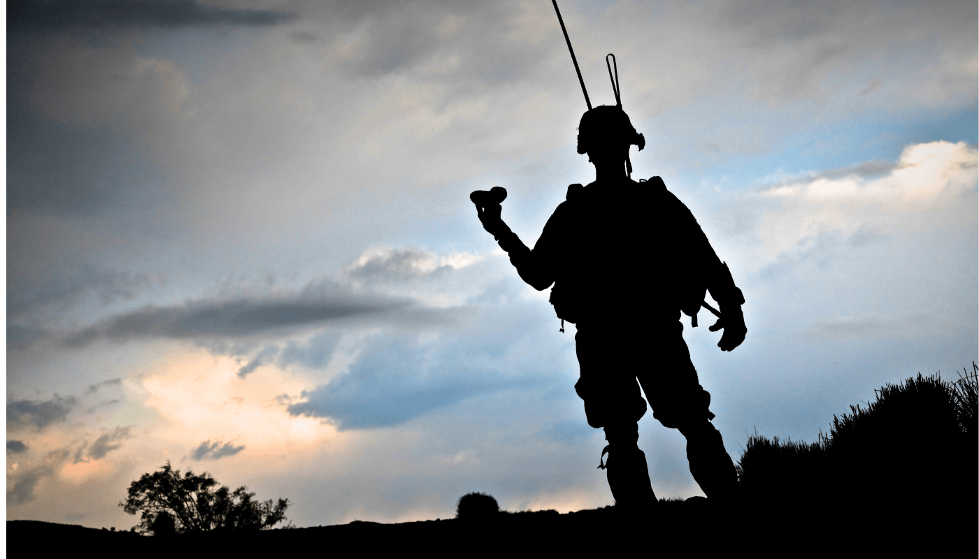 Silhouette d'un militaire avec équipement de parachutisme contre un ciel nuageux, symbolisant engagement et préparation.