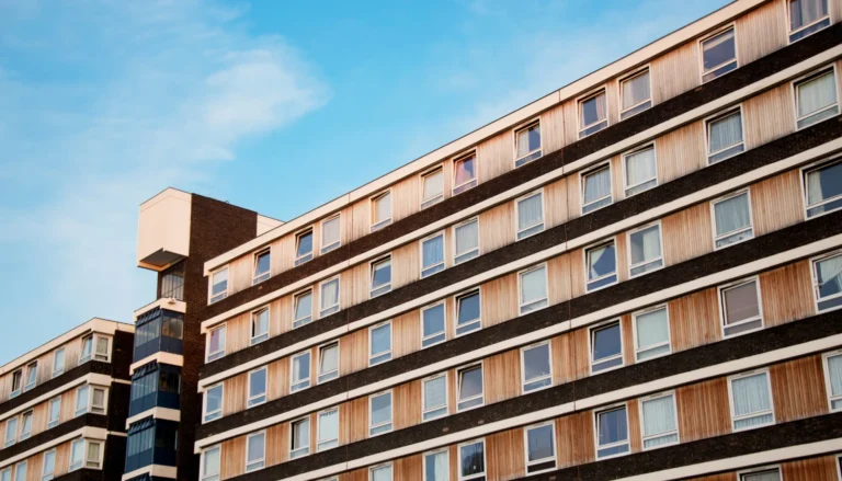 Façade d’un immeuble résidentiel moderne avec plusieurs étages, fenêtres en bois et structure en béton, représentant des services en droit immobilier et immobilier commercial offerts par Haas Avocats.