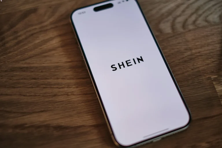Application Shein sur smartphone affichant le logo, illustrant la digitalisation des services juridiques et la proximité avec les clients.