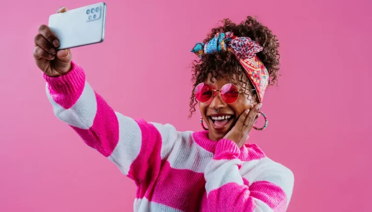 Jeune femme souriante avec lunettes roses, prenant un selfie, illustrant la législation des influenceurs en 2026.