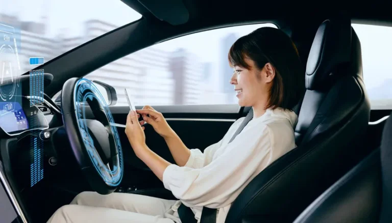 Femme utilisant un smartphone dans une voiture autonome moderne, illustrant la responsabilité en cas d’accident de véhicules autonomes.