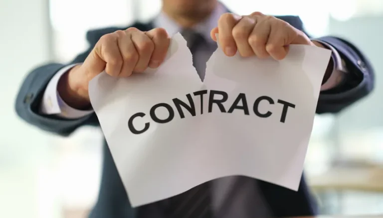 Personne en costume déchirant un papier avec le mot 'CONTRAT' pour symboliser la rupture contractuelle.