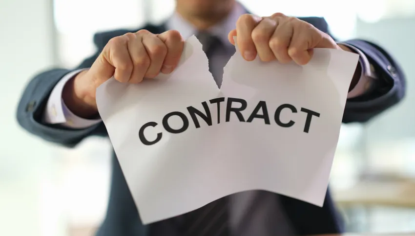 Personne en costume déchirant un papier avec le mot 'CONTRAT' pour symboliser la rupture contractuelle.